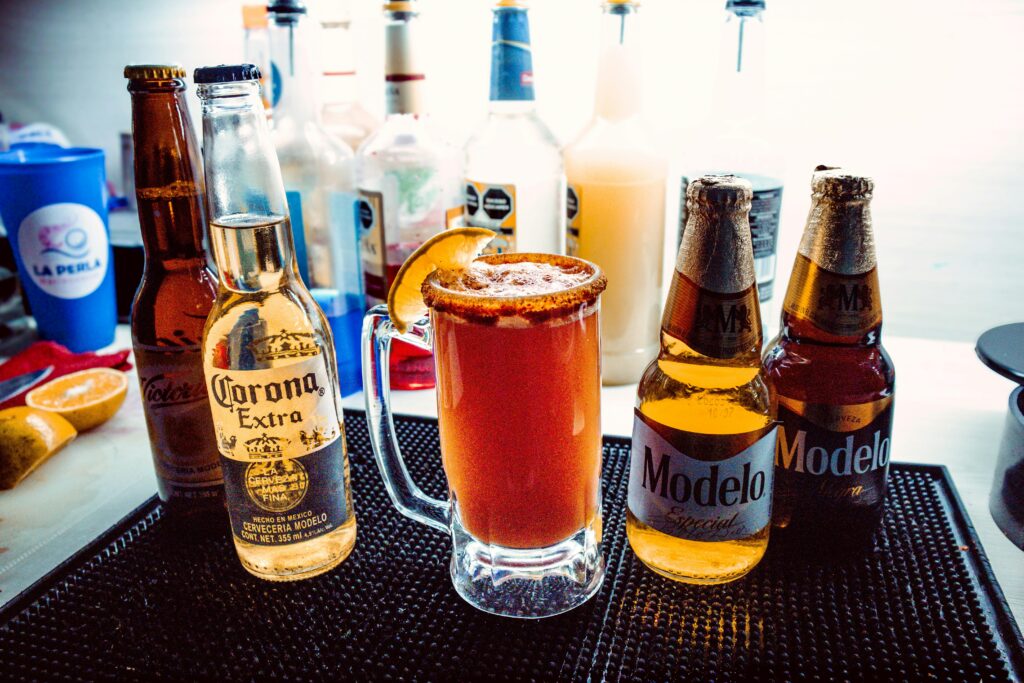 Chilled Michelada with beer bottles on bar counter, perfect for a refreshing drink moment.