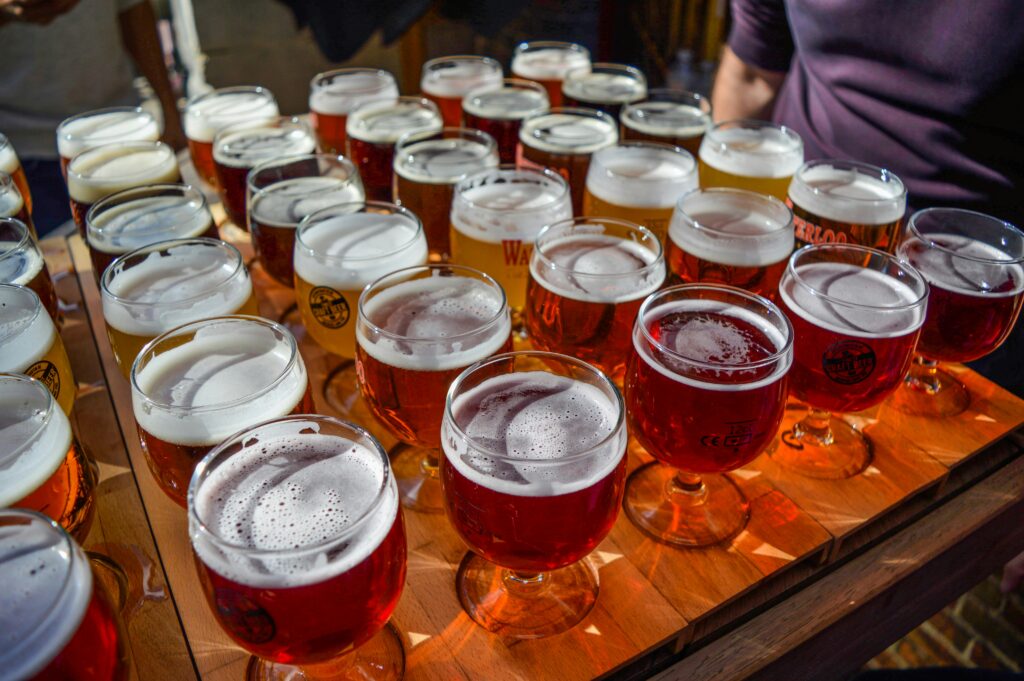 From above of crop unrecognizable male client choosing fresh delicious beer from different varieties in street cafe